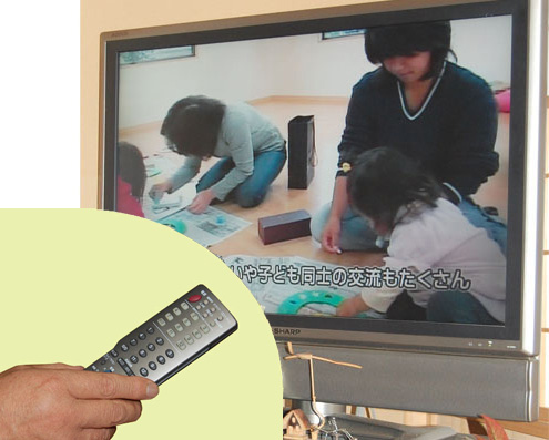 写真11　ONUからテレビがつながっている。コミュニティ・チャンネルを視聴しているところ。リモコンの黒いボタンがデジタル放送用、サービスが始まれば意識しないで使える準備ができている（白がアナログ用）