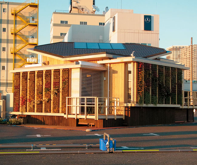 写真9　慶應義塾大学：慶應型共進化住宅（Keio Co-Evolving House）。交差積層集積材パネル（杉集成材）を用いた純国産材の木造住宅。屋上・壁面に緑化を図っている。屋根部分に太陽熱利用暖房・給湯装置や太陽電池パネル、環境センサーなどが見られる。