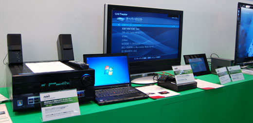 写真6　ロヴィ社のWindows7「Play To」に対応したDLNA製品のデモ。AVアンプの新モデルTX-NA5007（写真左）をWindows7 PC（写真中央）と、イーサネットで接続。PC側がAVアンプを認識し、最新のWindows Media Player上でAVアンプを音声出力機器として選び、音楽ファイルを再生できる。中央は大型テレビ画面。その前のボックスは、DTCP-IP対応HDネットワークメディアアダプタ。右端は無線LAN接続でPCからの写真、音楽、ビデオ等のデジタルコンテンツを再生するフォトフレーム。その隣（右端）のDTCP-IP対応NAS（Network Attached Strage）メディアサーバも接続されてデモ。