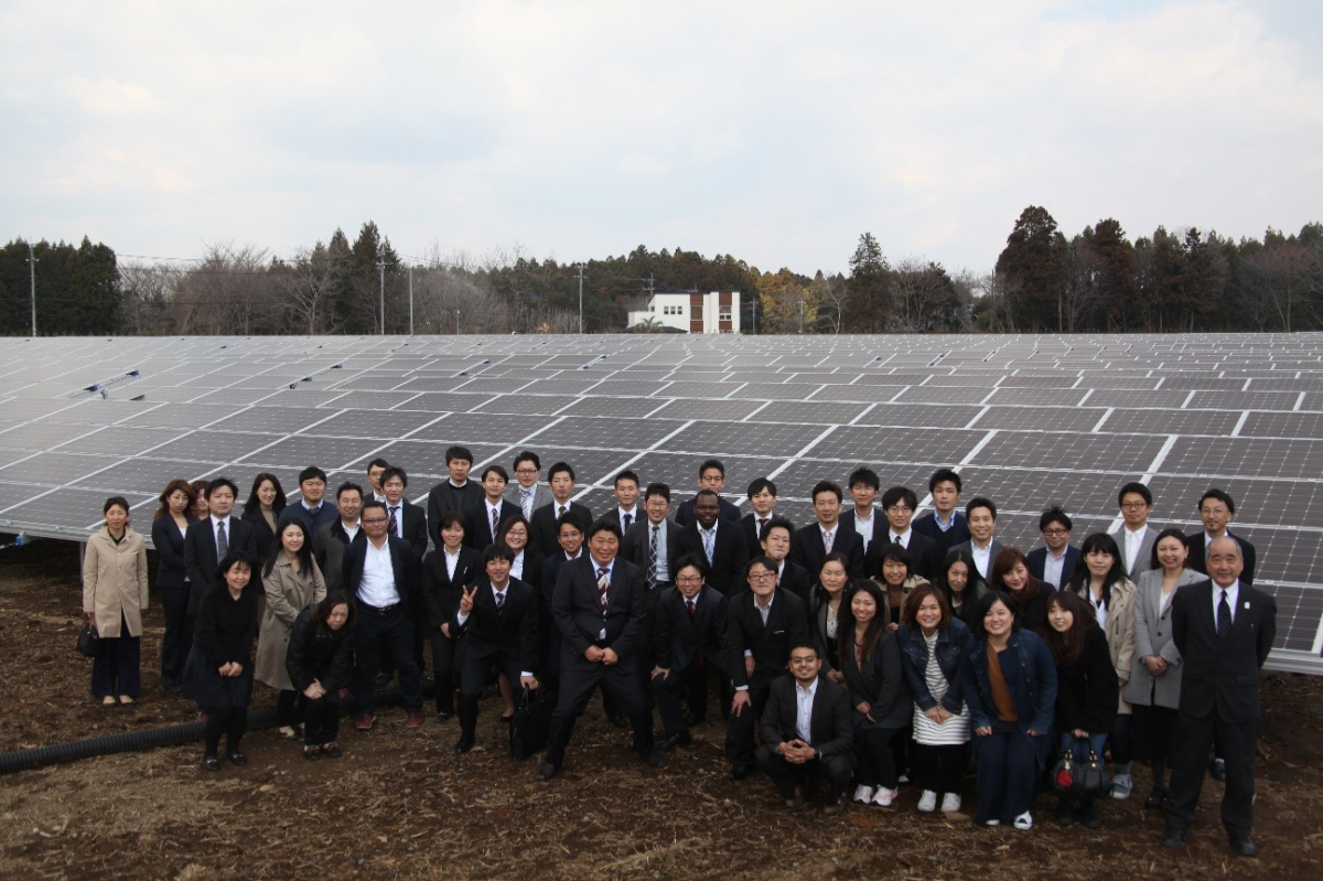 図　「春の木ソーラー発電所」を背に、関係者と従業員が集まったところ