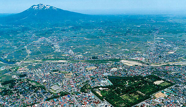 写真1　岩木山と弘前公園を中心とした弘前市街。市の中心に岩木川が流れている。〔写真提供：弘前市〕