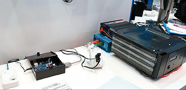 写真4　畜エネとしてのリチウム電池（右側。BAYSUN製、容量：1.4kWh）。中央はスマートコンセント。左端の白い小さな箱はHEMSとPoE（100BASE-T）で接続されたECHONET Lite対応の温度センサー（プロトタイプ。PoEから給電されるため電池が不要）。PoE：Power over Ethernet、イーサネットケーブルを通じて、イーサネットHUBから、端末（センサー等）に直流電力を供給する技術。