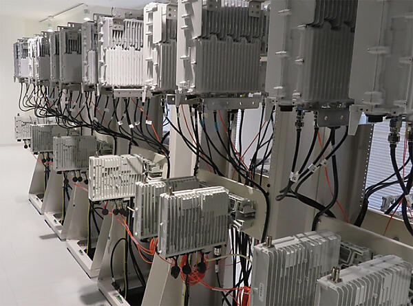 写真3　基地局設備エリア　（1）上段設備：RHH（Remote Radio Head、リモート無線装置）。基地局設備の1つ。主に無線信号の送受信を行う。ビルの屋上などに設置される。　（2）下段設備：RIU（Radio Interface Unit、無線インタフェースユニット）。回線終端装置であり、インタフェースの変換器。