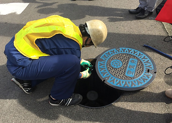 図　マンホールに試験用のLTE-M通信端末を取り付けているところ